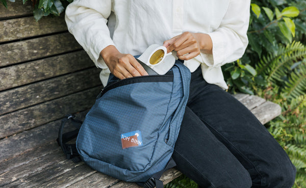 A person retrieving a pair of sunglasses from the horizontal slash pocket.